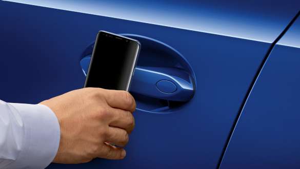 Close-up of the driver's door of the BMW 3 Series Sedan with a Samsung mobile phone held in front of the door handle.