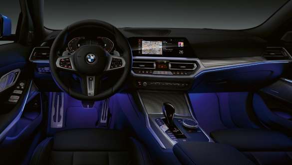 Front view of the driver's cockpit of the BMW 3 Series Sedan with by Ambient light blue illuminated legroom.