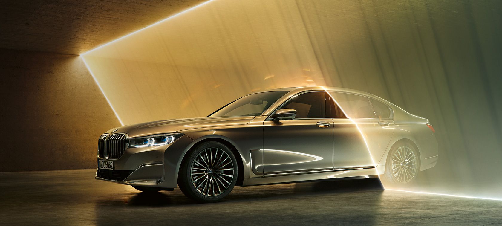 Front view of driving BMW 5 Series Sedan by day under glass building.