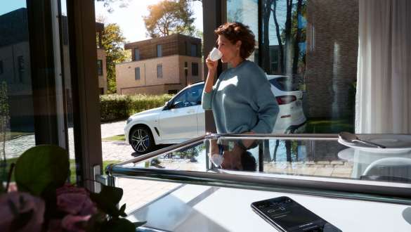 Woman drinking a cup of coffee while she updates the software of her BMW X5 via Remote Software Upgrade G05 2018