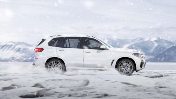 Driving mode xSnow BMW X5 G05 2018 Mineral White metallic side view driving on snow